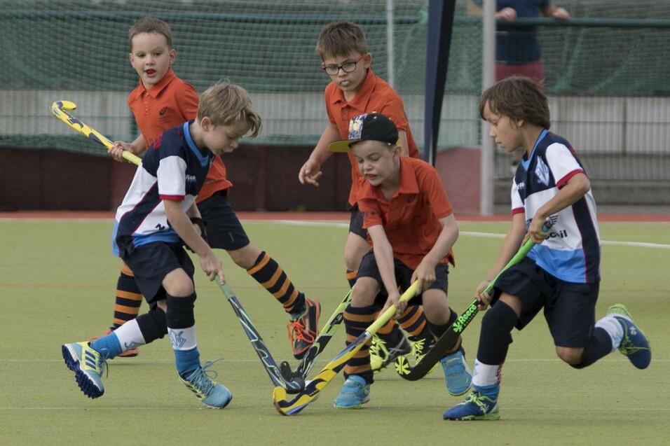 Gruppe von Kindern welche Hockey mit Schlägern spielen Gruppe von Kindern welche Hockey mit Schlägern spielen
